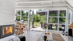 Un intérieur moderne agrémenté d’une cheminée, de meubles en bois et de grandes fenêtres offrant une vue sur l’extérieur.
