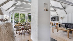 Un vaste espace de vie doté d’un haut plafond, de parquet et d’une grande fenêtre donnant sur un paysage verdoyant.