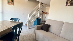 Un soggiorno moderno con un tavolo da pranzo, un divano e una scala che conduce a un piano superiore.