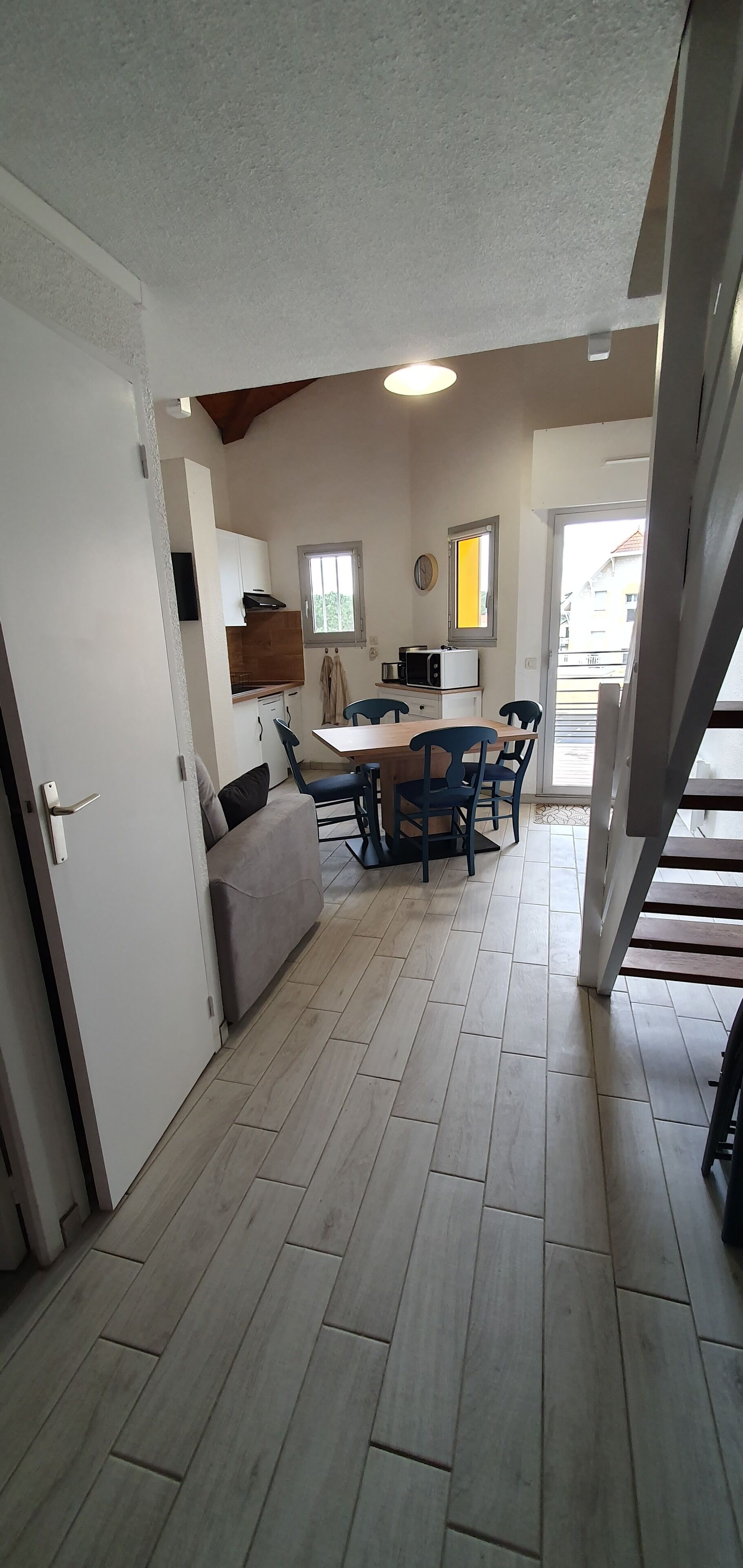 Une cuisine compacte avec un coin repas, un plancher en bois et une vue sur l’extérieur.