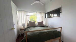 A bedroom with a single bed, a ceiling fan, a window with curtains, and a small bedside table with a lamp. - Surrounded by Nature With Panoramic Mountain Views (Lower Beechmont)