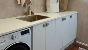 A compact laundry area with a washing machine, a sink, and storage cabinets. - Surrounded by Nature With Panoramic Mountain Views (Lower Beechmont)