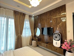 A modern bedroom with a bed, a TV, a fan, and a decorative mirror. - Yusuf Baba Shortlets (Abuja)