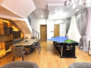 A modern room with a pool table, dining area, and a staircase. - Yusuf Baba Shortlets (Abuja)