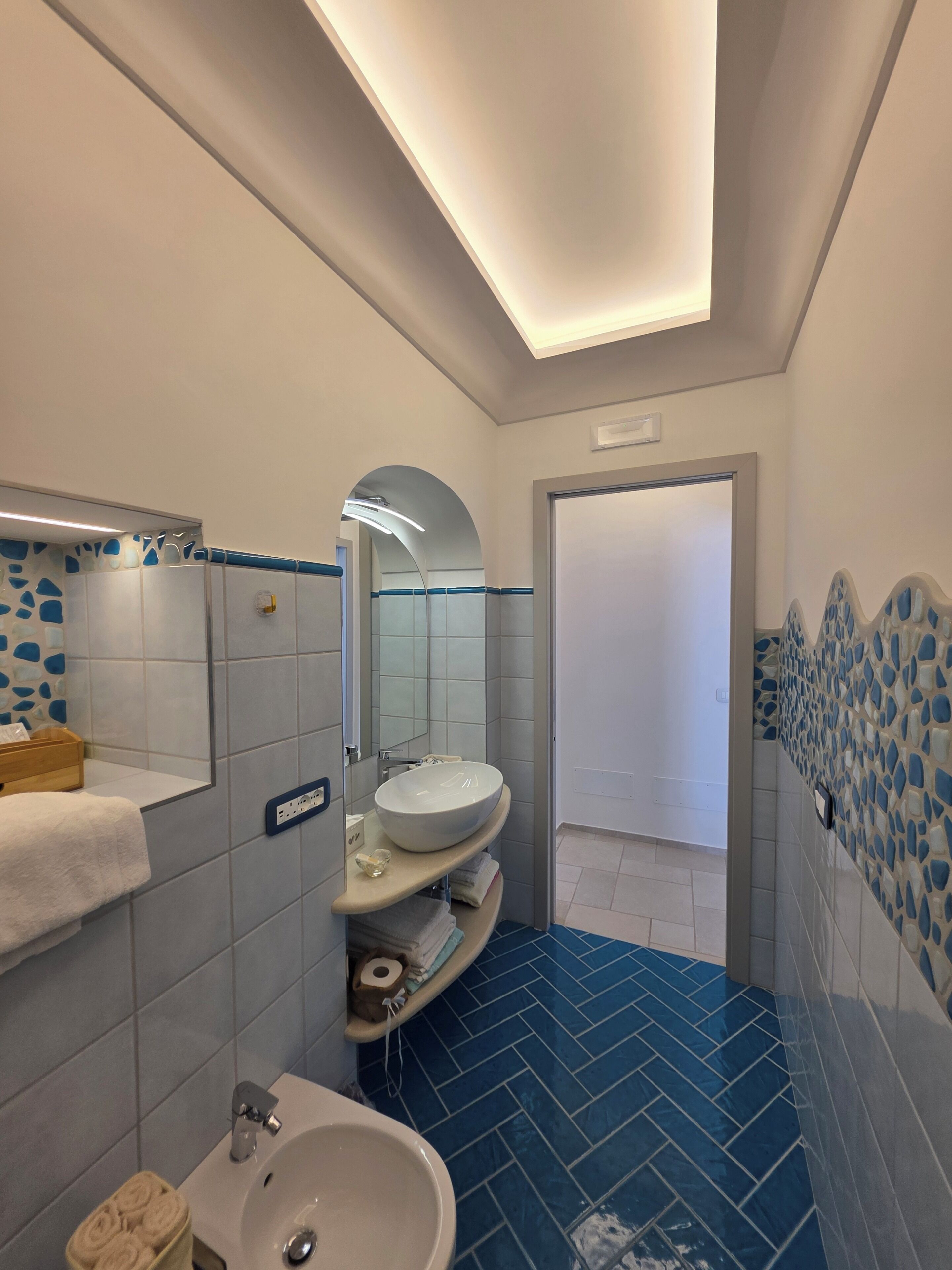 Un baño moderno con un lavamanos grande, espejo y zona de ducha.