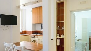 Una cocina moderna con armarios de madera, estufa integrada y un comedor con mesa de madera y sillas blancas.