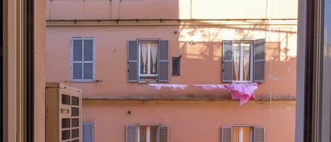 A balcony with a washing machine, a small table, and a basket.