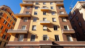 Un edificio de apartamentos de varios pisos con balcones, ventanas grandes y un cielo azul despejado.