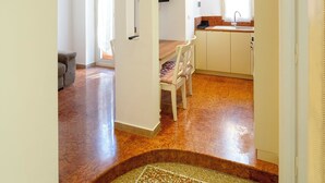 Amplia sala de estar con mesa y sillas de comedor, una cocina con ventana y un pasillo que conduce a otra habitación.