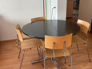 Une table ronde avec six chaises, une prise de courant et une porte ornée d’une bande colorée.