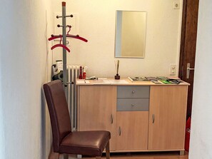 A small room with a brown leather chair, a wooden cabinet with drawers, a radiator, and a coat rack with red items. - Casa Giovanna Ronco sopra Ascona by Interhome (Ronco sopra Ascona)