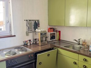 Une cuisine équipée d’une cuisinière, d  ’un évier et de meubles de rangement verts.