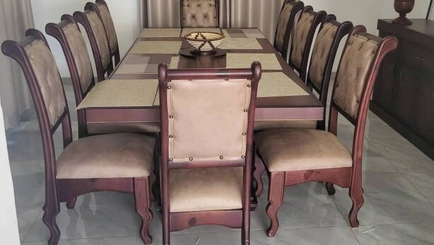 A dining area with a rectangular table surrounded by six upholstered chairs with wooden frames. - Familyfriendlyhome4u (Bulawayo)