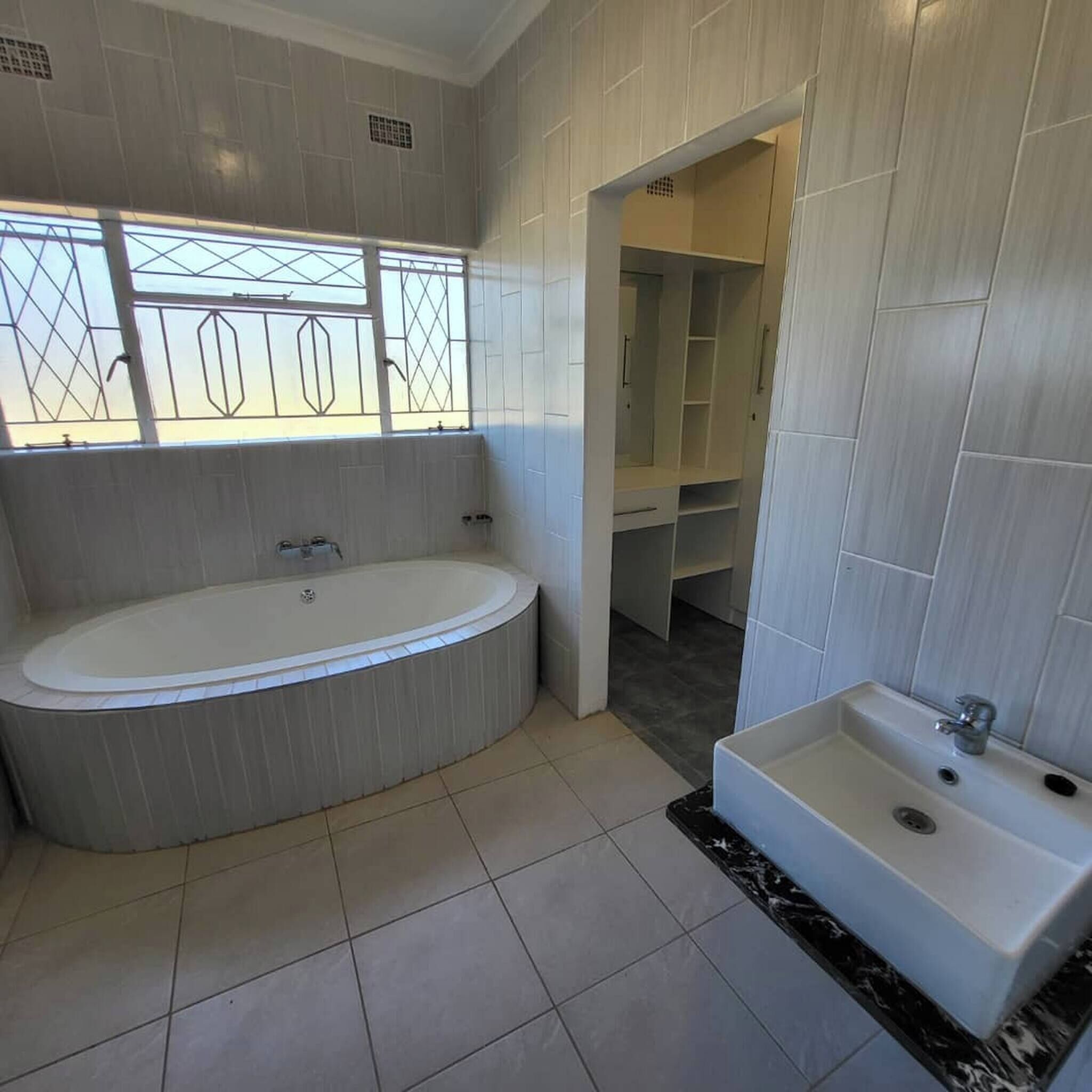 Un baño moderno con una bañera independiente, un lavabo empotrado y una ducha a ras de suelo.