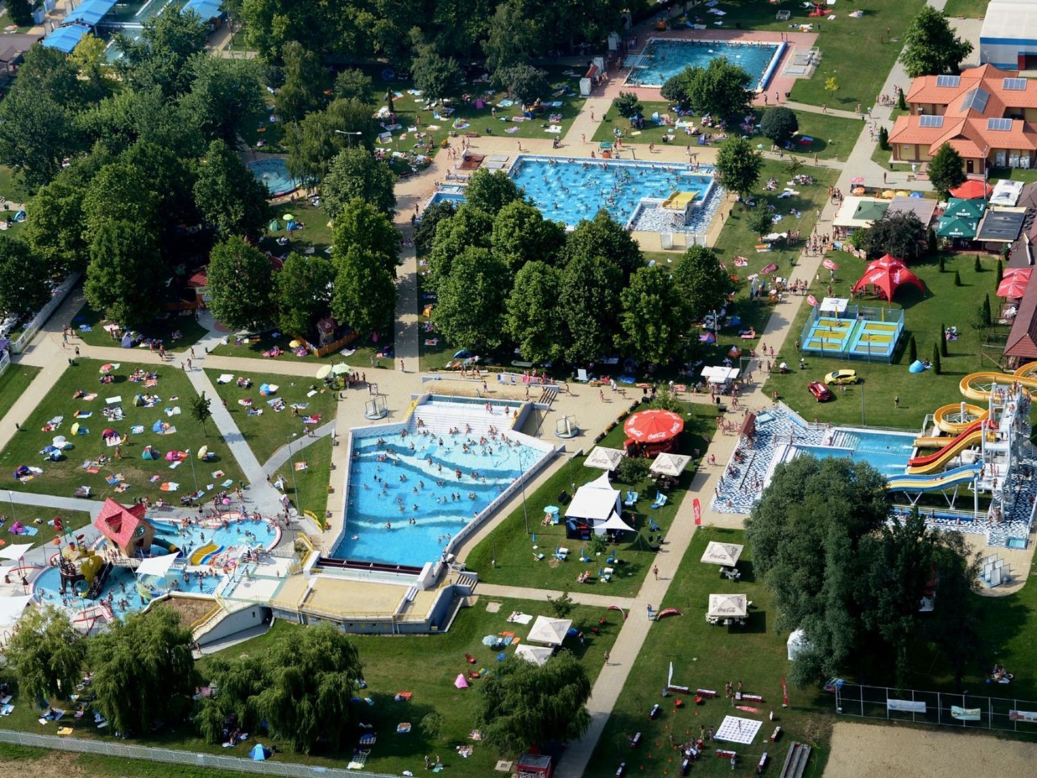 Vue aérienne d’un parc aquatique comprenant plusieurs piscines, des toboggans et une grande structure de toboggan aquatique.