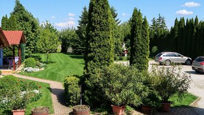 Un jardín bien cuidado con diversas plantas en macetas, un pabellón y un césped.
