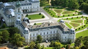 Un edificio grande e histórico, con múltiples cúpulas y un jardín de diseño simétrico.