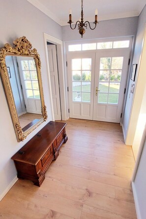Ein geräumiges Zimmer mit großem Spiegel, Holzboden und einer Kristallleuchtre.