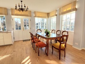 Ein geräumiger Speisesaal mit einem großen Holztisch, sechs Stühlen und einem Kronleuchter.