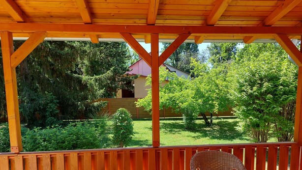 A covered outdoor area with a wooden deck, a wicker chair, and a table. - 100 Meter vom Strand by Interhome (Zamardi)