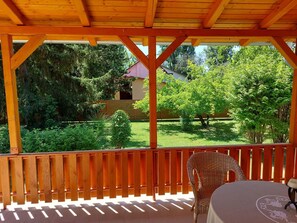 Un espace extérieur abrité, doté d’une terrasse en bois, d’une chaise en osier et d’une table.