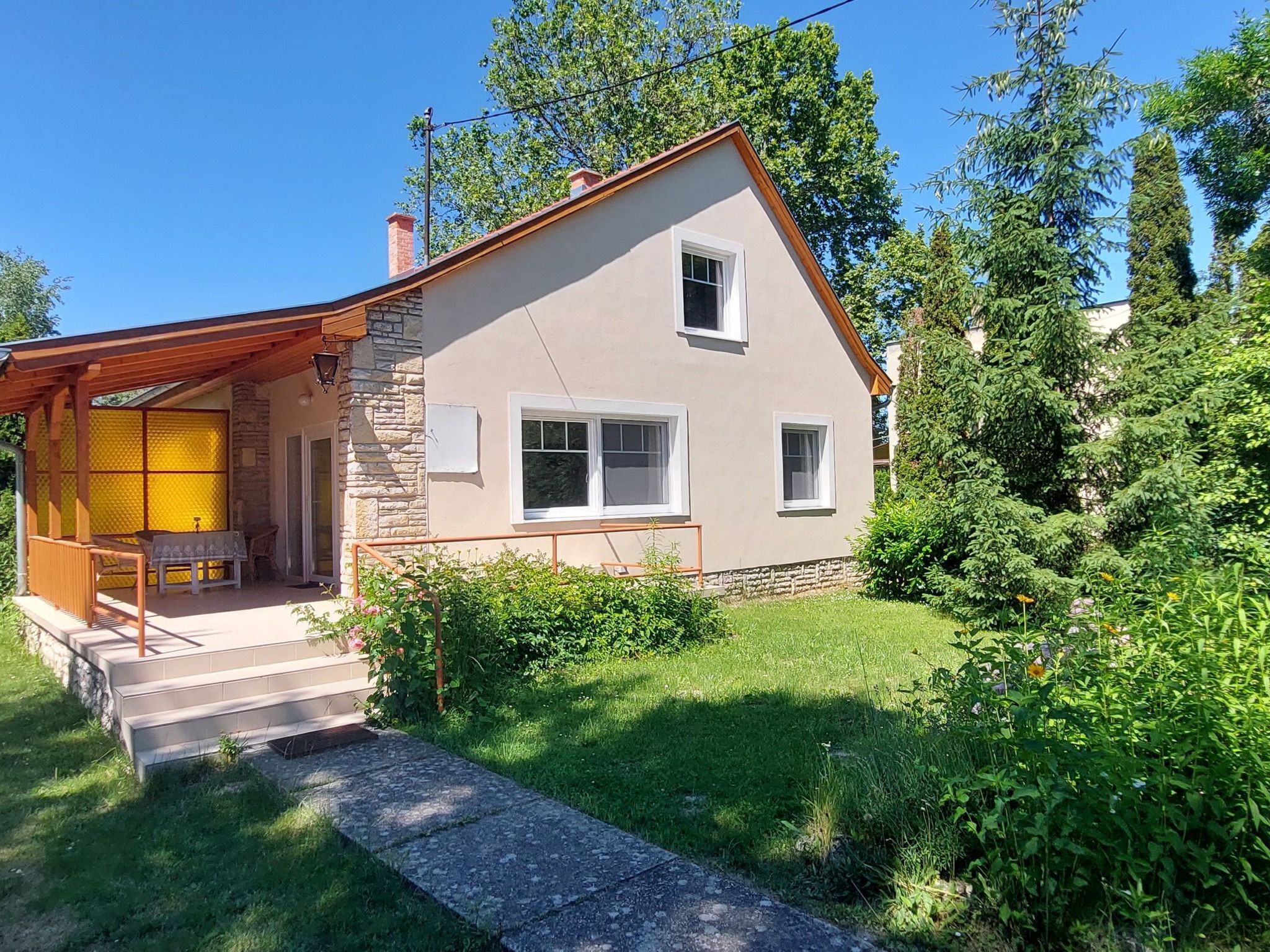 A two-story house with a stone facade, a covered porch, and a well-maintained garden.