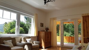 A spacious living room with a large window, a chandelier, and a view of a garden through the glass doors. - 100 Meter vom Strand by Interhome (Zamardi)