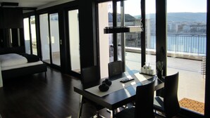 A modern hotel room with a large bed, a dining area, and a balcony with a city view. - Penthouse mit Donaublick by Interhome (Budapest)