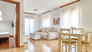 A modern living room with a sofa, a glass dining table with chairs, a small coffee table, and a TV mounted on the wall. - Wohnung "Lux" mit Meerblick by Interhome (Herceg Novi)