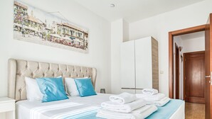 A hotel room with a bed, a painting of a street scene, a wardrobe, and a door. - Wohnung "Lux" mit Meerblick by Interhome (Herceg Novi)