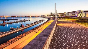 A waterfront promenade with a paved walkway, a marina with boats, and buildings in the background. - Strand und Natur auf den Azoren by Interhome (Ponta Delgada (Açores))