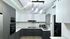 A modern kitchen with a central island, built-in appliances, and pendant lighting.