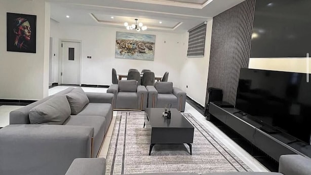 A modern living room with grey sofas, a coffee table, and a flat-screen TV.