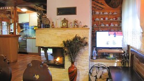 A cozy living room with a fireplace, wooden shelves with decorative items, and a television. - Holiday Home, Nowa Kaletka (Purda)
