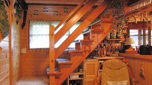 A cozy cabin interior with a wooden staircase, a bar area, and a chair with a pillow. - Holiday Home, Nowa Kaletka (Purda)