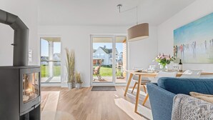 Un salon moderne doté d’une cheminée, d’un coin repas et d’une grande fenêtre donnant sur un jardin.