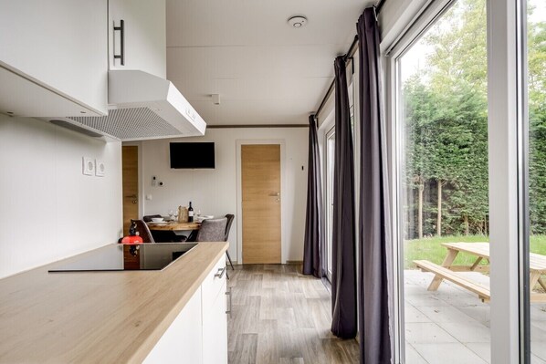 Una cocina moderna con encimera de madera, estufa integrada y zona de comedor con mesa y sillas.