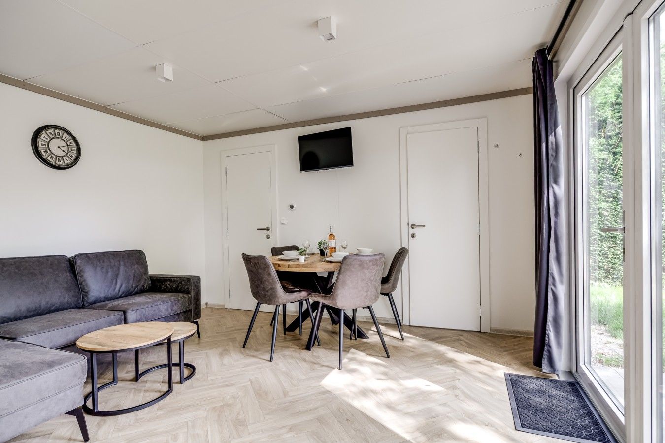 Een moderne woonkamer met een bank, salontafel en een eettafel met stoelen.