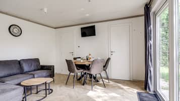 Een moderne woonkamer met een bank, salontafel en een eettafel met stoelen.