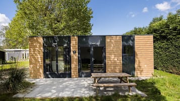 Een modern gebouw met een houten gevel, grote glazen deuren en een picknicktafel ervoor.