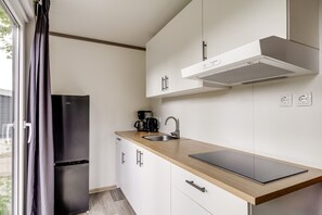 A modern kitchen with a built-in refrigerator, a coffee maker, a sink, and a laptop on the counter.