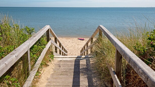 A wooden staircase leading to a sandy beach with a calm sea in the background. - Strandkieker - Cozy apartment with sea view (List auf Sylt)