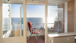 A balcony with a view of the sea, a chair, a table, and a radiator. - Strandkieker - Cozy apartment with sea view (List auf Sylt)