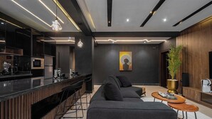 Una cocina moderna con encimera negra, electrodomésticos de acero inoxidable e iluminación colgante.