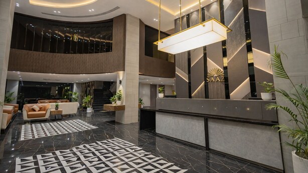 A modern lobby with a reception desk, seating area, and a staircase. - Saaz Hotel, Club & Convention Centre (Indore)