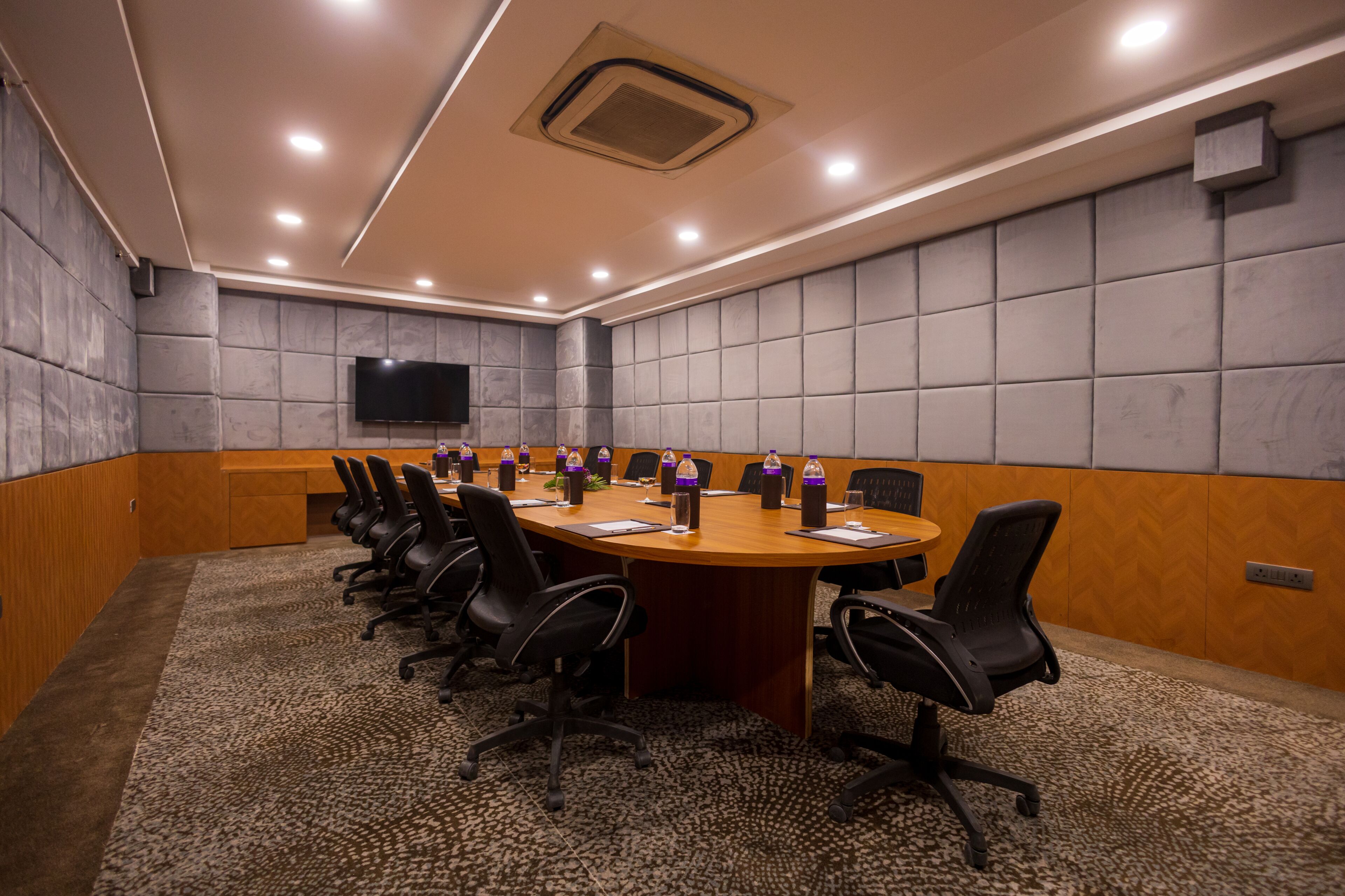 Une salle de conférence avec une longue table, des chaises et un téléviseur à écran plat fixé au mur.