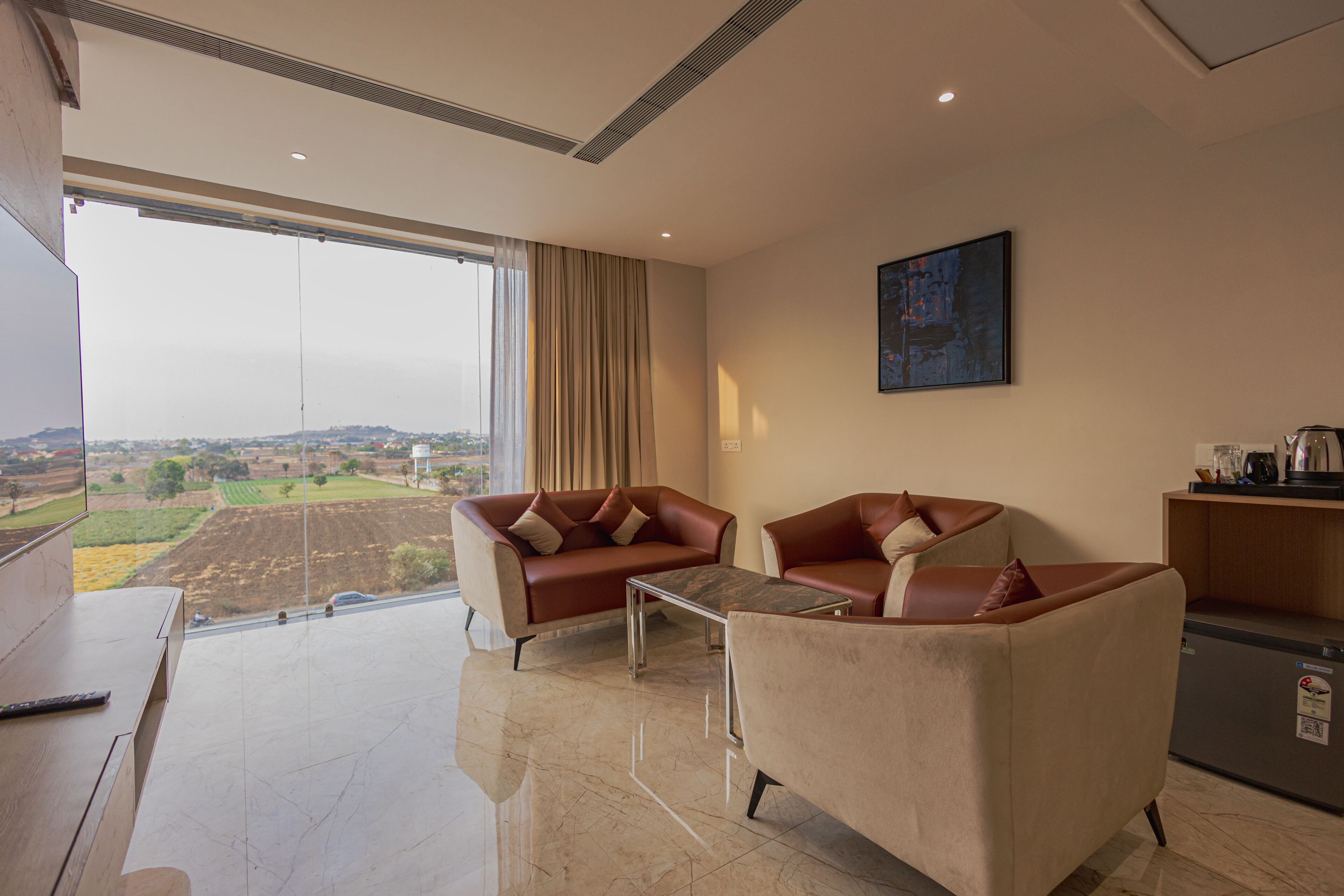 A modern living room with two sofas, a coffee table, and a view of a landscape through large windows.