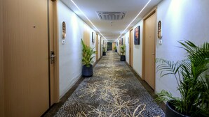 A hotel hallway with doors, potted plants, and a patterned carpet. - Saaz Hotel, Club & Convention Centre (Indore)