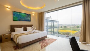 A modern hotel room with a large bed, a painting, a view of the countryside, and a balcony. - Saaz Hotel, Club & Convention Centre (Indore)