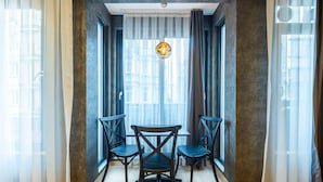 A room with a modern design, featuring a dark-colored wall, a wooden floor, and a dining area with a table and four chairs. - the business class suit karkoy (Istanbul)